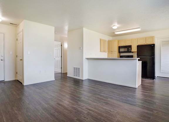 A kitchen area with a white counter and a black fridge.