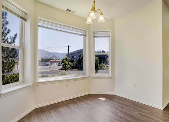 A room with a view of a street and houses outside the window.