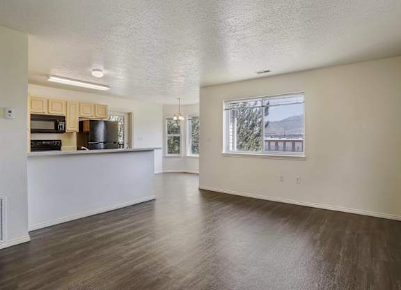 A spacious room with wooden floors and a large window.