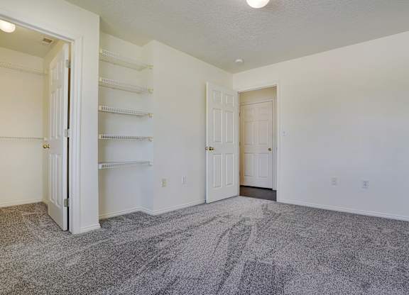 A large, empty room with a grey carpet and white walls.