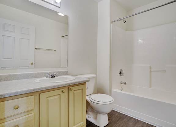 A white toilet sits in a bathroom next to a sink and bathtub.