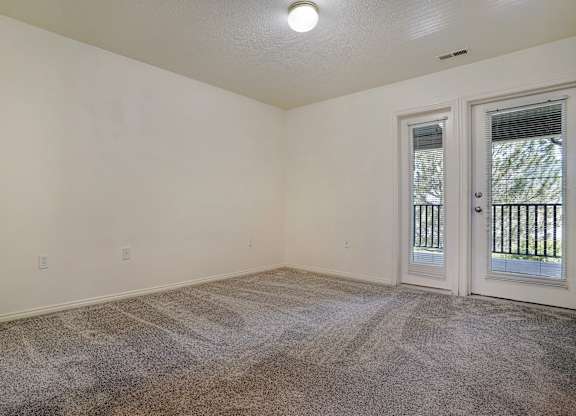A room with a carpeted floor and a door leading outside.