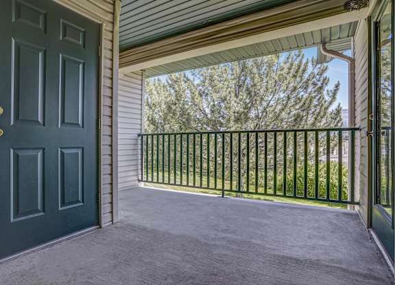 A black door is on the left of a balcony with a metal railing.