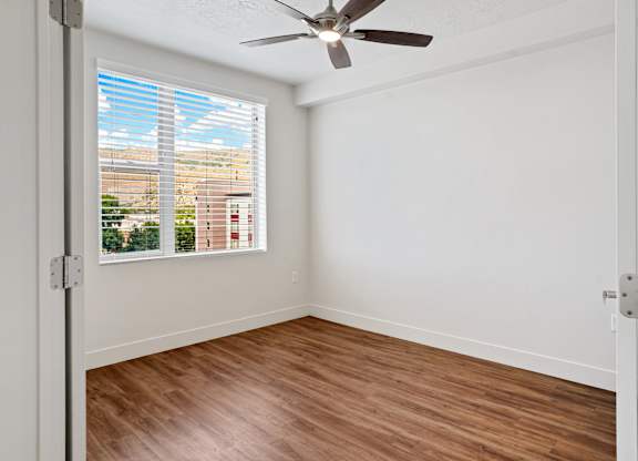 an empty room with a large window and a ceiling fan