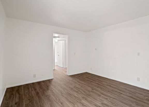 a bedroom with hardwood floors and white walls
