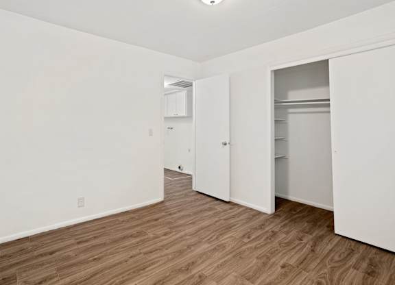 a bedroom with white walls and hardwood floors
