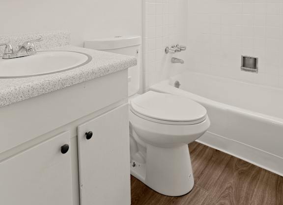 a bathroom with white fixtures and a wooden floor