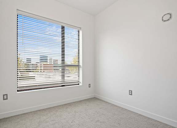 an empty room with a large window with blinds