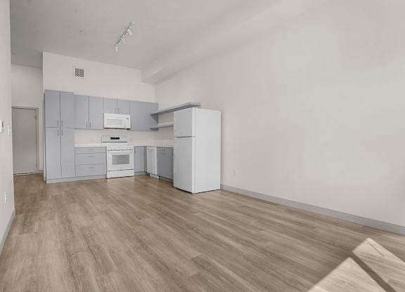 A kitchen with white cabinets and a wooden floor.