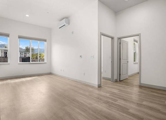 A room with a wooden floor and a window overlooking a building.