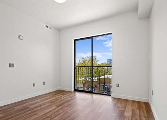 an empty living room with a sliding glass door to a balcony