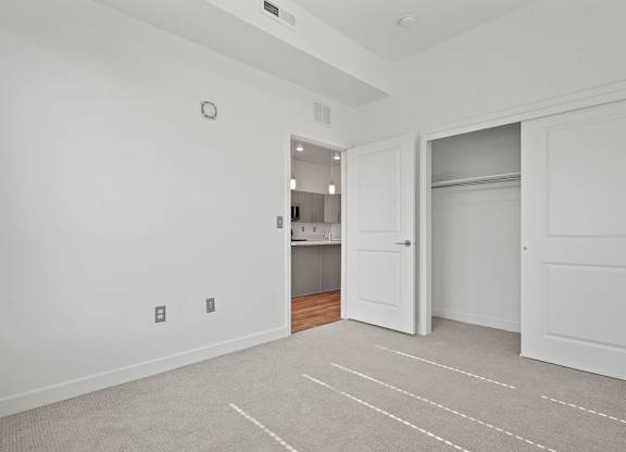 a bedroom with a closet and a door to a kitchen