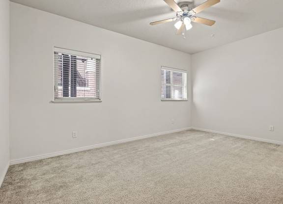 an empty living room with a ceiling fan and a window