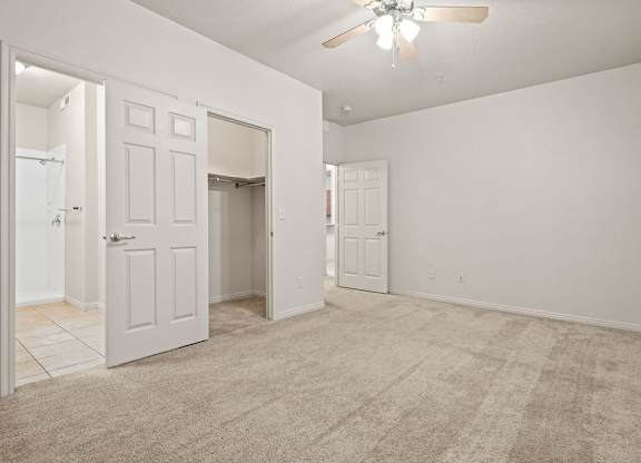 an empty living room with a ceiling fan and a door to a closet