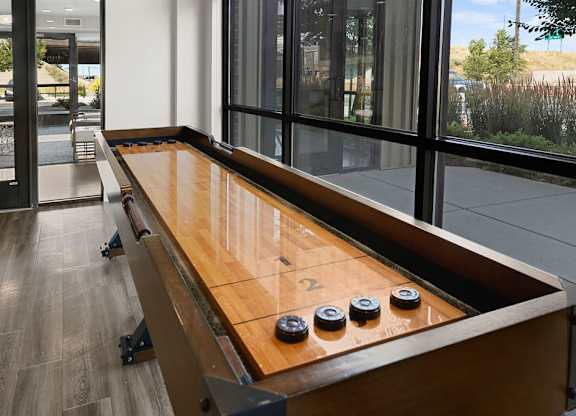a shuffleboard table in a living room with large windows
