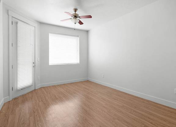 an empty room with wood floors and a ceiling fan