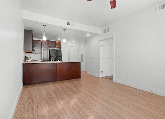 an empty living room and kitchen with wood flooring