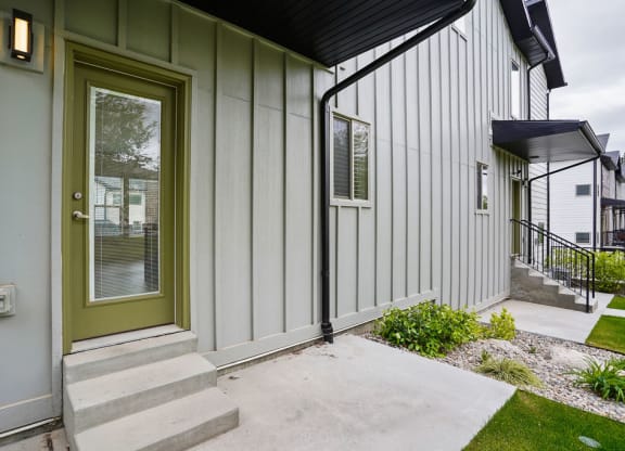 the front door of a home with steps and a sidewalk