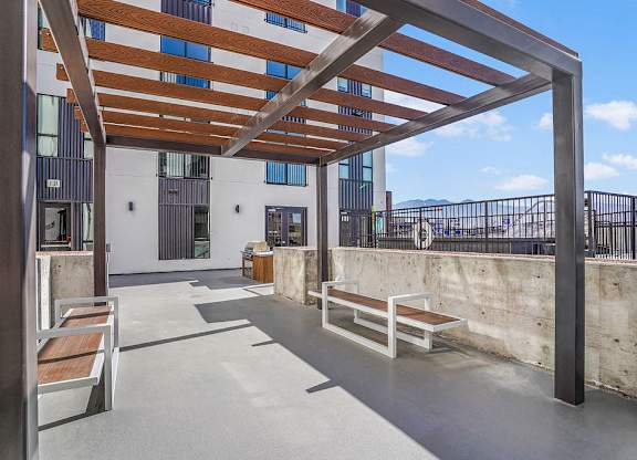 A patio with a wooden pergola and benches.