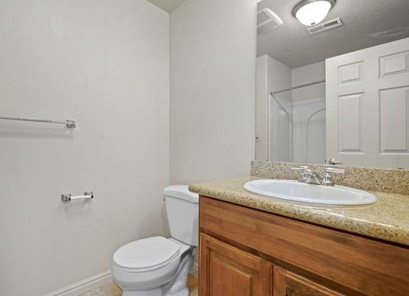 A bathroom with a toilet, sink, and mirror.