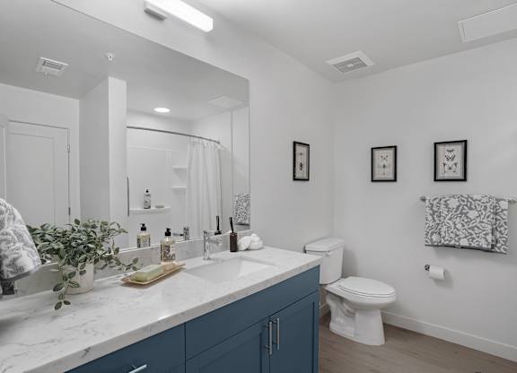 A bathroom with a white counter top and blue cabinets.