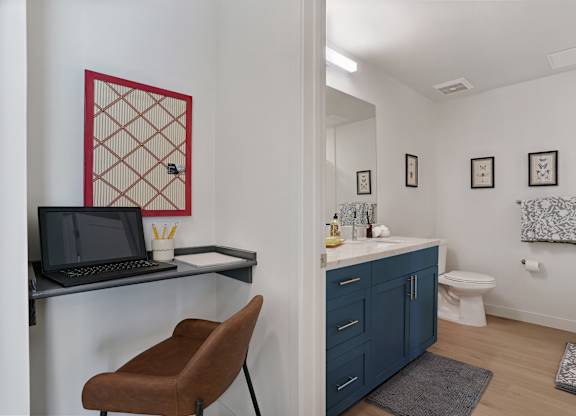 A bathroom with a toilet, sink, and a chair.