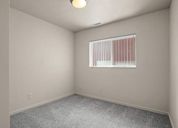 A room with a window covered by blinds and a ceiling light.