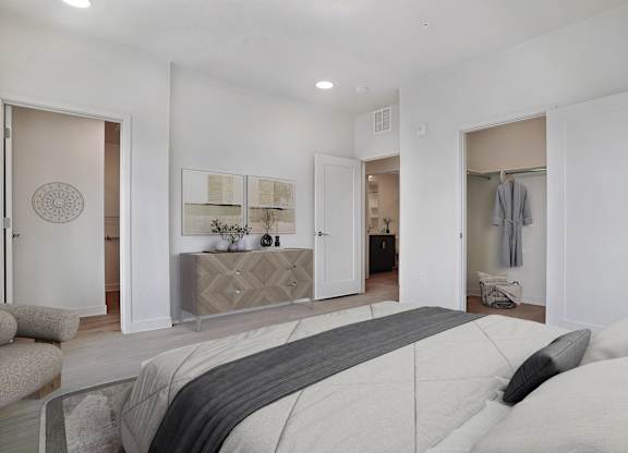 A bedroom with a large bed and a dresser with a mirror above it.