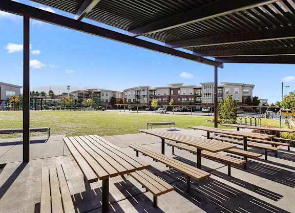 a park with picnic tables and buildings in the background