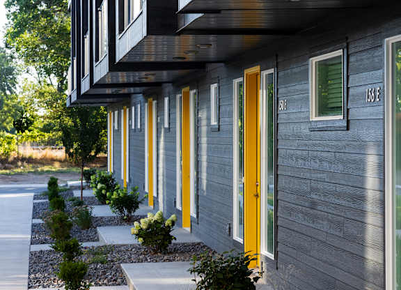 A line of modern houses with grey siding and yellow doors.