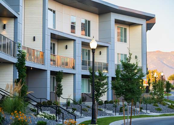 A modern apartment building with balconies and flower beds in front.