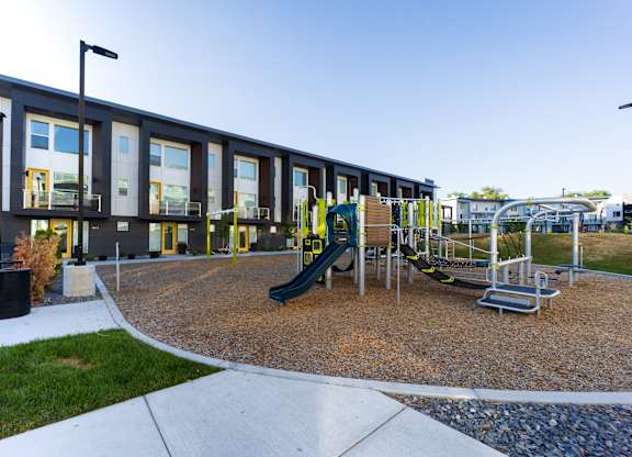A playground with a green slide and a yellow railing.