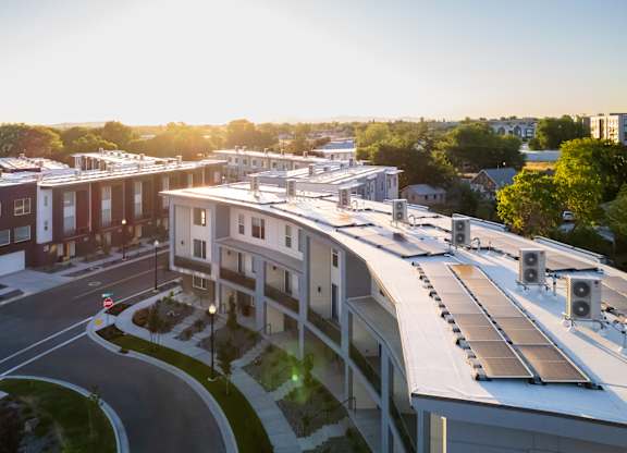 A sunny day in a residential area with apartment buildings and solar panels on the roofs.