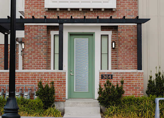 A red brick house with a green door and a black lamp post in front.