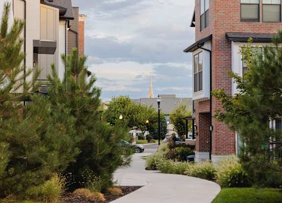 A walkway between two buildings with trees on the side.