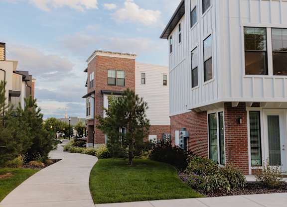 A long concrete walkway leads between two rows of modern apartment buildings.