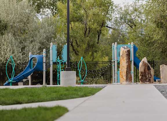A playground with a blue slide and a wooden rock climber.