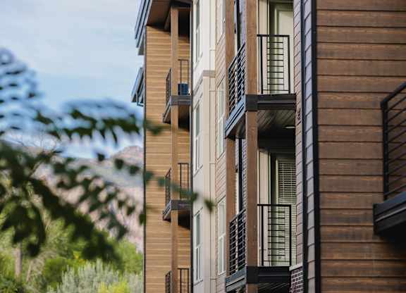 A modern apartment building with balconies and a walkway in front.