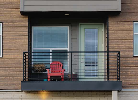 A balcony with a red chair and a wreath on the door.