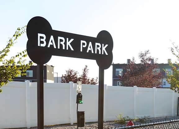 A sign that says Bark Park stands in front of a fence.