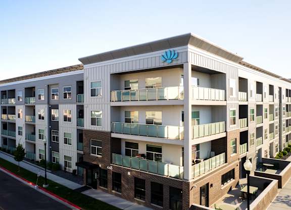 A modern apartment building with a blue logo on the top floor.