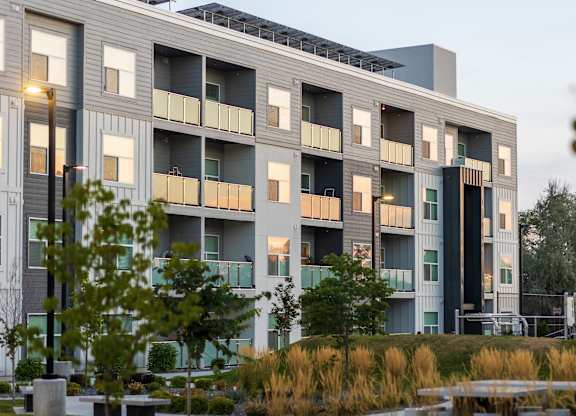 A modern apartment building with balconies and greenery in the foreground.