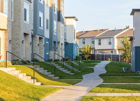 A residential area with apartment buildings and a sidewalk.