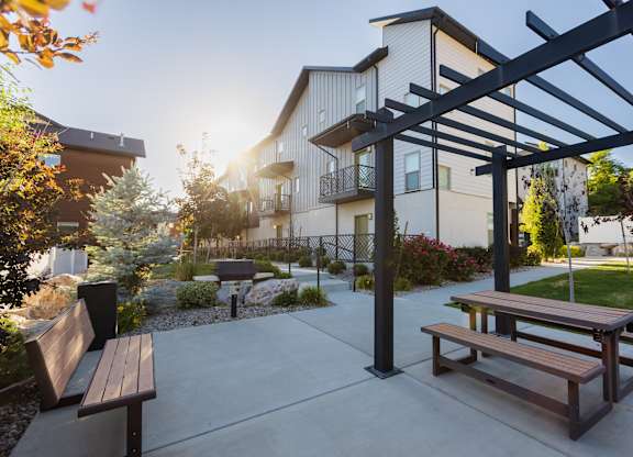 A sunny day at a park with benches and a picnic table.