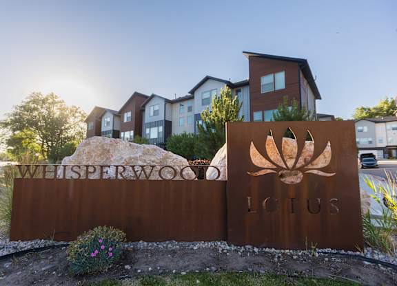 A sign for Whisperwood Lotus in front of a building.