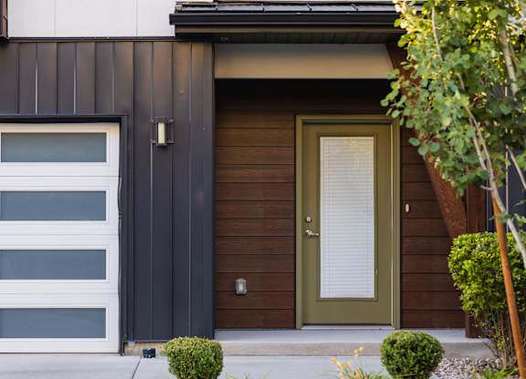 A modern house with a white garage door and a green door.