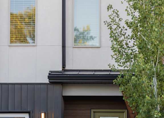 A modern house with a brown door and a grey garage door.