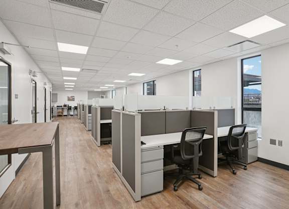 A long hallway with cubicles and chairs on the side.