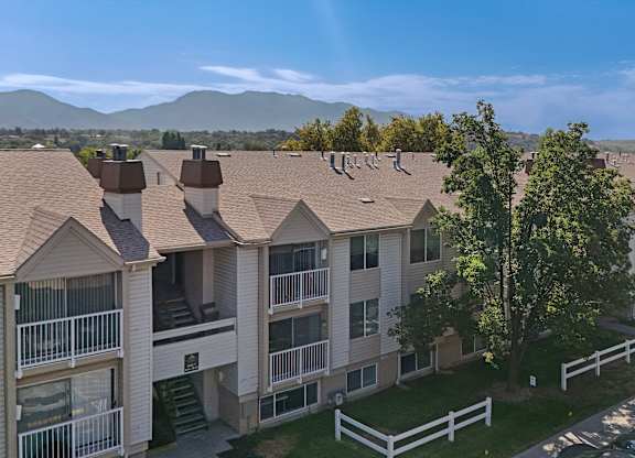 Apartment complex with a white fence in front.