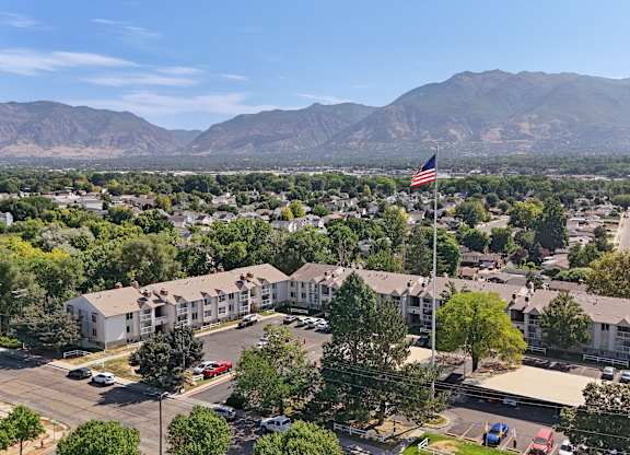 A large American flag flies in front of a building with a parking lot in front of it.